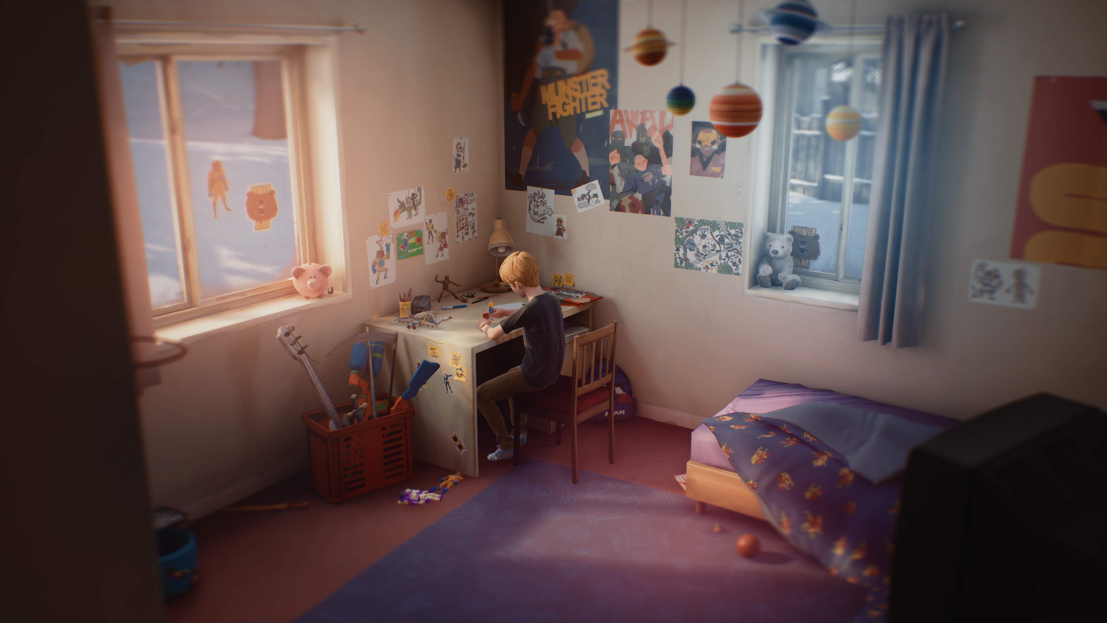 A young boy, Chris, sits at the desk in his bedroom, playing. A display of the planets hangs from the ceiling.