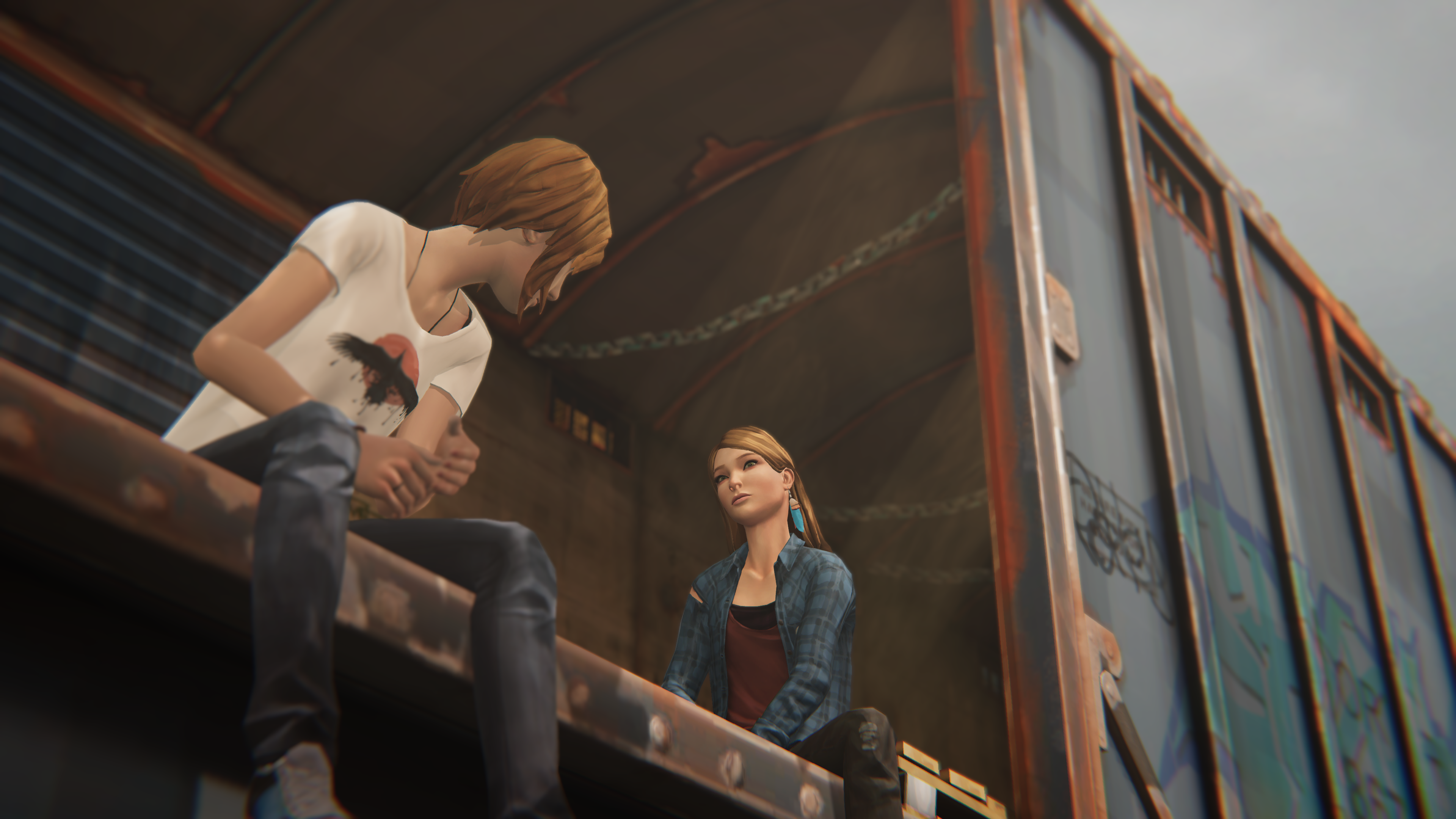 Chloe's legs dangle over the side of an open train box-car, as she talks with Rachel Amber.